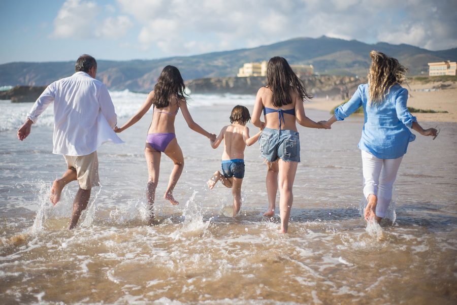 A family running hand in hand into the ocean