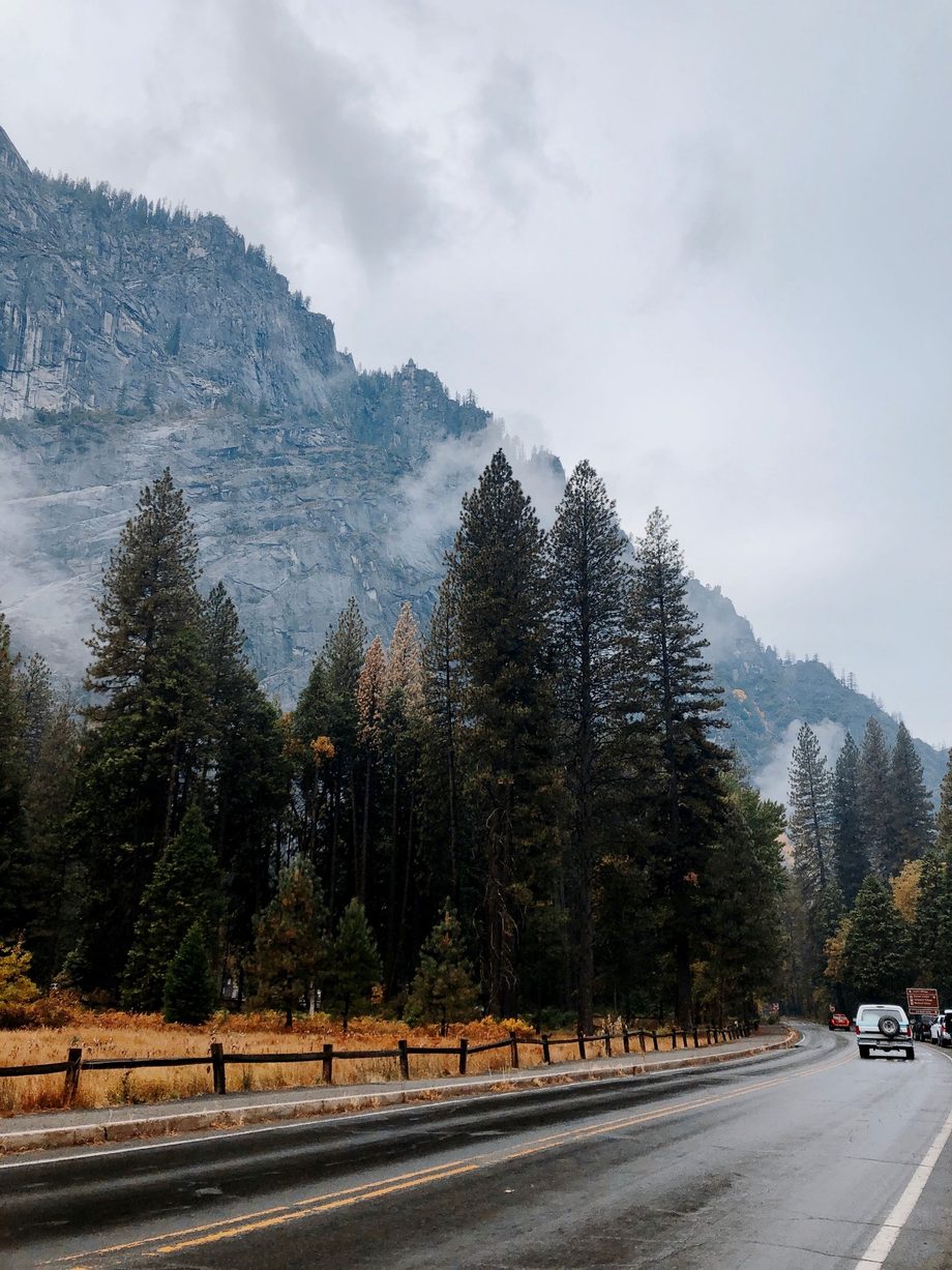 A mountain road running below granite cliffs under low cloud