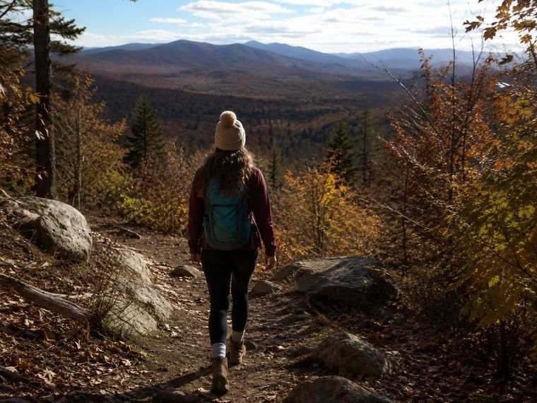 A woman hiking alone on a mountain trail in autumn
