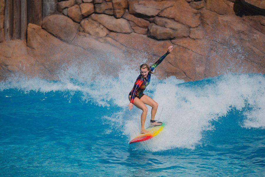 A woman surfing a bright blue wave