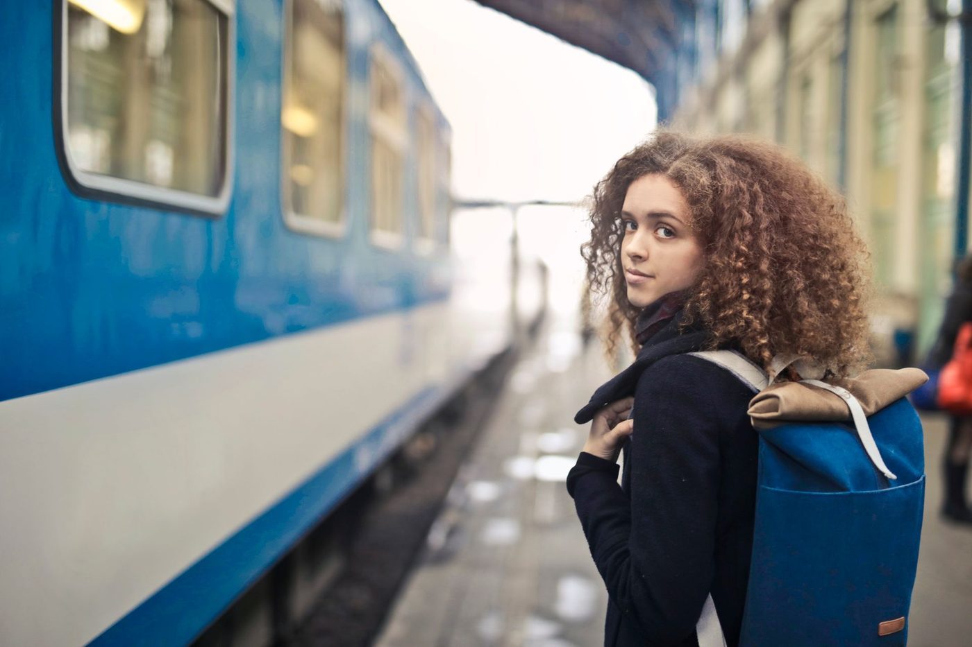 A woman with a backpack waiting on a train platform