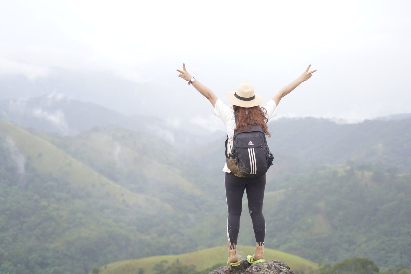 A woman standing on a mountain summit with her arms raised
