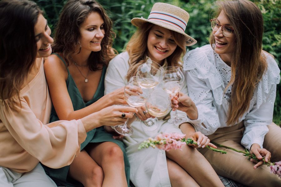 Four friends toasting with glasses in a garden