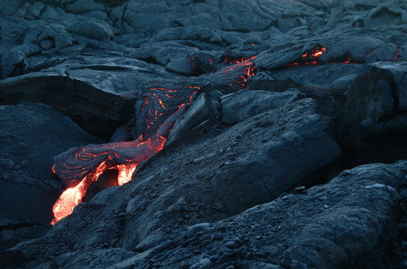 Glowing lava flowing across black volcanic rock in Hawaii