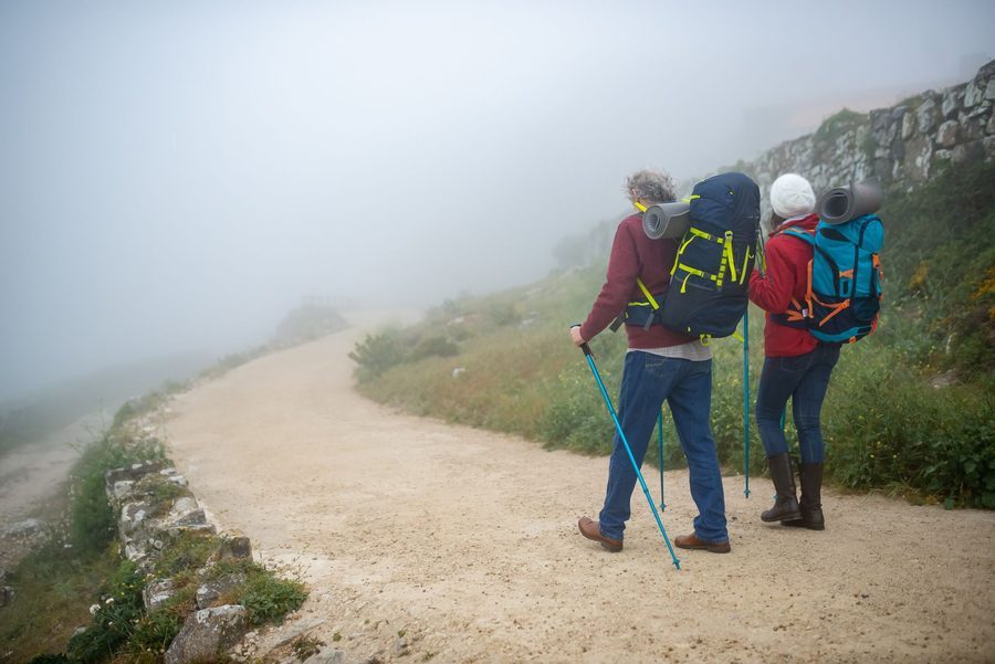 Two travelers hiking a misty trail with backpacks
